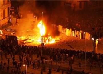 kelompok-pro-dan-anti-mubarak Kedua kelompok massa pro Mubarak dan anti-pemerintah sama-sama berkemah di tahrir Square. Sebuah mobil terbakar di dekat barikade yang memisahkan kedua kelompok